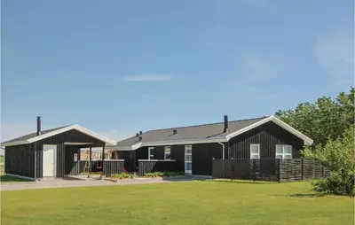 a house with a black roof and a yard at Four-Bedroom Holiday Home In Lokken in Løkken