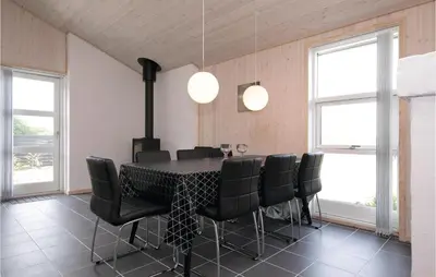 a dining room with a table and black chairs at Four-Bedroom Holiday Home In Lokken in Løkken