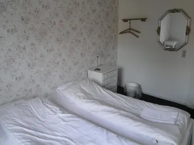 a bedroom with a white bed with a dresser and a mirror at Thinghuskroen in Vestervig