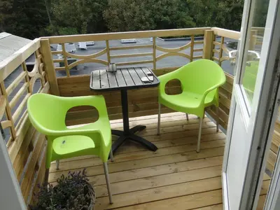a balcony with a table and two green chairs at Thinghuskroen in Vestervig