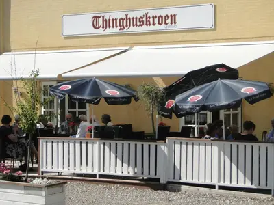 a restaurant with umbrellas in front of a building at Thinghuskroen in Vestervig