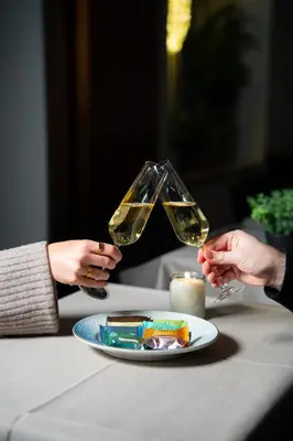 two people holding wine glasses over a plate of food at Palads Hotel in Viborg