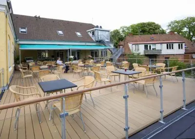 a deck with tables and chairs on a building at Hotel Højslev Kro in Højslev