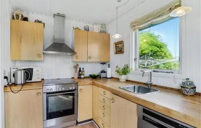 a kitchen with wooden cabinets and a sink and a window at Two-Bedroom Holiday Home In Lemvig in Lemvig