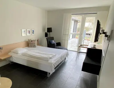 a bedroom with a white bed and a large window at Hotel Strandtangen in Skive