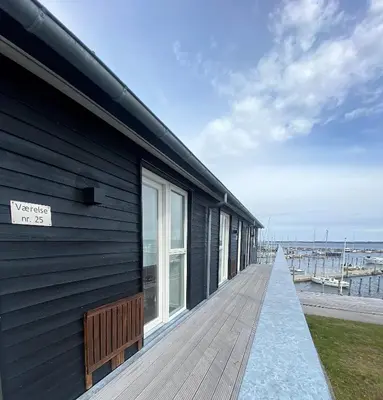 a building with a wooden walkway next to the water at Hotel Strandtangen in Skive