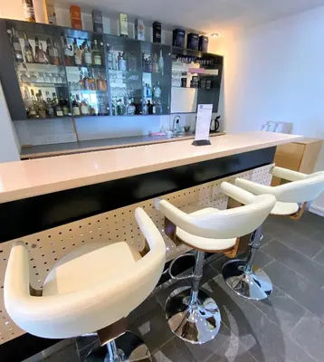 a bar with white bar stools and a counter at Hotel Strandtangen in Skive