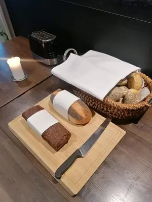a basket of bread and a knife on a cutting board at Hotel Strandtangen in Skive