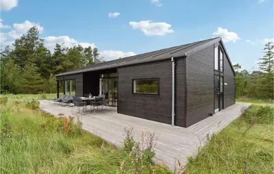 a black house with a wooden deck in a field at Three-Bedroom Holiday Home In Fjerritslev in Fjerritslev