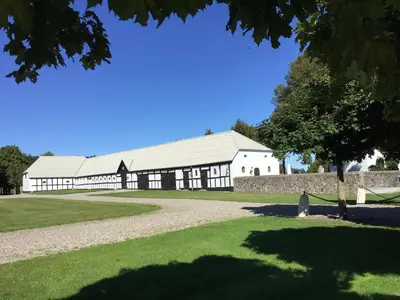 a large white building with a tree in the foreground at Sebber Kloster in Nibe