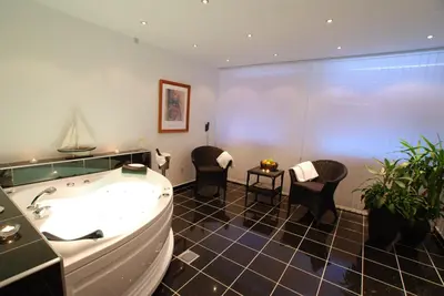 a large bathroom with a tub and two chairs at Hotel Pinenhus in Glyngøre