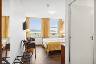 a hotel room with a bed and a window at Hotel Pinenhus in Glyngøre