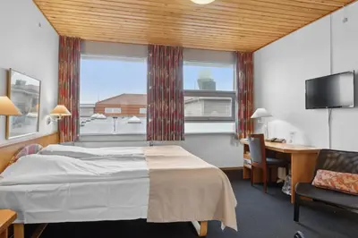 a hotel room with a bed and a desk and a window at Hotel Pinenhus in Glyngøre
