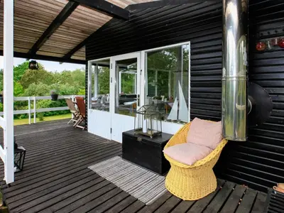 a screened porch with a wicker chair on a deck at 4 person holiday home in Højslev in Højslev
