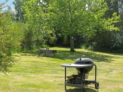 a grill in a field with a bench in the background at 4 person holiday home in Højslev in Højslev