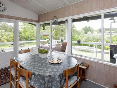 a dining room with a table and chairs and windows at 4 person holiday home in Højslev in Højslev