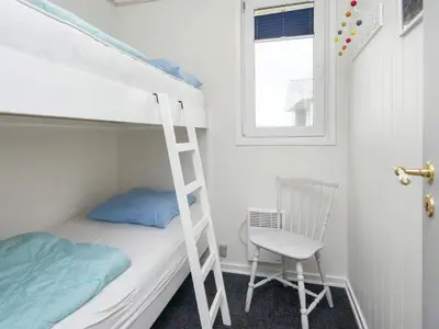 a bunk bed with a ladder and a chair in a room at 5 person holiday home in Lemvig-By Traum in Trans