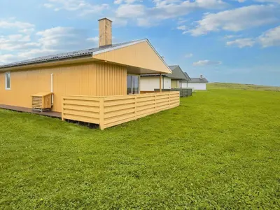 a yellow house with a large green field next to it at 5 person holiday home in Lemvig-By Traum in Trans