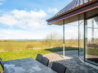 a patio with a table and chairs and a field at Luxury Fjordview Retreat-By Traum in Højslev