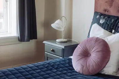 a bedroom with a bed with a pink pillow on it at Hotel Lidenlund in Lemvig