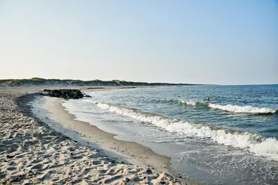 a sandy beach with waves coming into the ocean at Danhostel Fjaltring in Fjaltring
