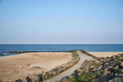a walkway on a beach next to the ocean at Danhostel Fjaltring in Fjaltring