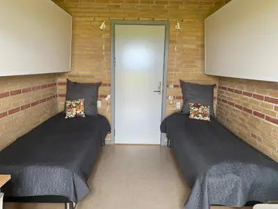 two beds in a room with brick walls at Danhostel Fjaltring in Fjaltring