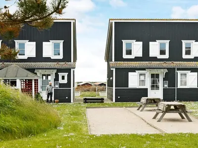 a man standing in front of a black house at 5 person holiday home in Vestervig-By Traum in Vestervig