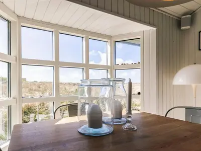 a glass vase sitting on a wooden table with windows at 6 person holiday home in Løkken-By Traum in Løkken