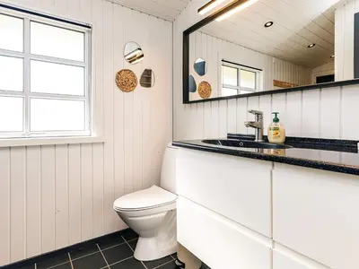 a bathroom with a toilet and a mirror at 6 person holiday home in Løkken-By Traum in Løkken