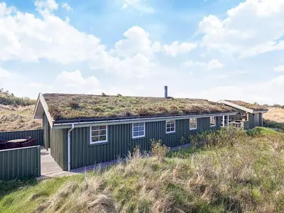 a house with a grass roof on the beach at 6 person holiday home in Løkken-By Traum in Løkken
