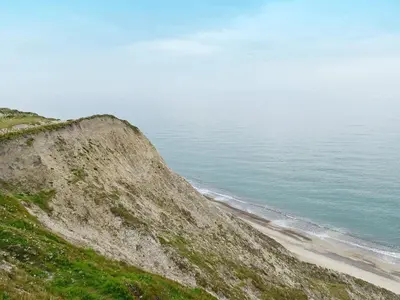 a hillside with a beach and the ocean at 6 person holiday home in Lemvig in Ferring