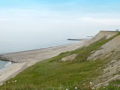 a sandy beach next to the ocean on a hill at 6 person holiday home in Lemvig in Ferring