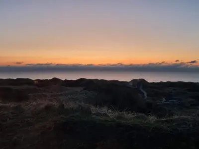 a sunset over a field with the ocean in the background at Modern Retreat with Spa - By Traum Ferienwohnungen in Løkken