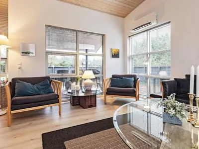 a living room with two chairs and a glass table at Modern Retreat with Spa - By Traum Ferienwohnungen in Løkken