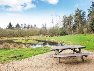 a wooden picnic table sitting next to a river at 5 person holiday home in Fur-By Traum in Fur