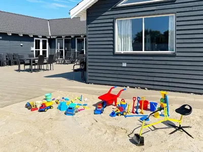 a pile of toys in the sand in front of a house at Luxury Retreat by Hostrup Beach - By Traum Ferienwohnungen in Spottrup