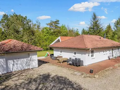 a white house with a table and chairs in a yard at 8 person holiday home in Højslev-By Traum in Højslev