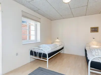 two beds in a room with white walls and a window at 10 person holiday home in Fur-By Traum in Fur