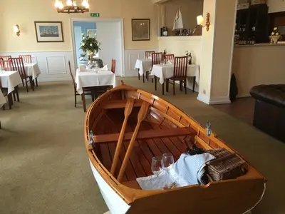 a wooden boat in a room with tables and chairs at Løgstør Badehotel - Hotel du Nord in Løgstør