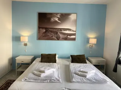 a bedroom with two beds and two lamps and a picture on the wall at Løgstør Badehotel - Hotel du Nord in Løgstør