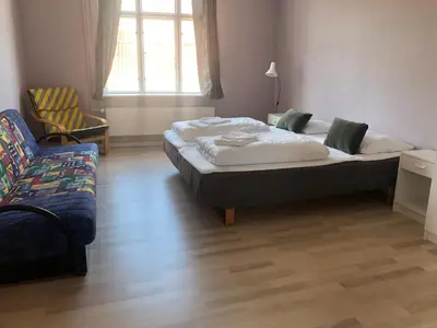 a bedroom with a bed and a chair and a couch at Løgstør Badehotel - Hotel du Nord in Løgstør