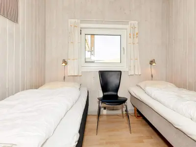 a room with two beds and a chair and a window at 10 person holiday home in Løkken in Løkken