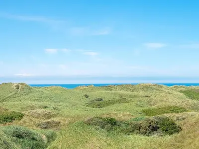a group of hills with the ocean in the background at 10 person holiday home in Løkken in Løkken