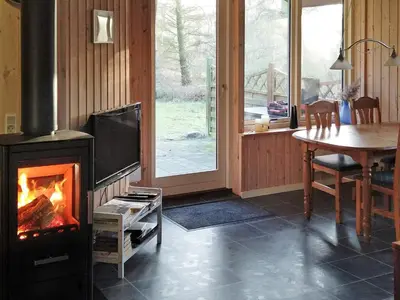 a living room with a fireplace with a table and a dining room at 6 person holiday home in Thyholm in Thyholm