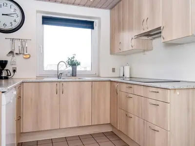 a kitchen with wooden cabinets and a clock on the wall at 12 person holiday home in Harboøre-By Traum in Harboør