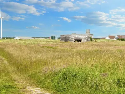 an old stone building in a field with a windmill at 12 person holiday home in Harboøre-By Traum in Harboør