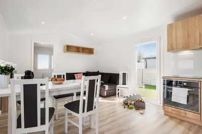 a kitchen and living room with a table and chairs at First Camp Klim Strand - Nordvestkysten in Fjerritslev
