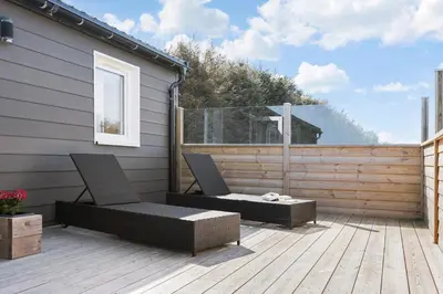 a patio with two chairs on a wooden deck at First Camp Klim Strand - Nordvestkysten in Fjerritslev