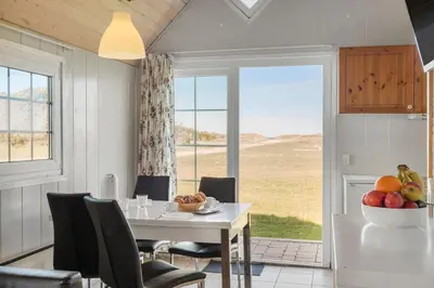 a dining room with a table and chairs and a window at First Camp Klim Strand - Nordvestkysten in Fjerritslev